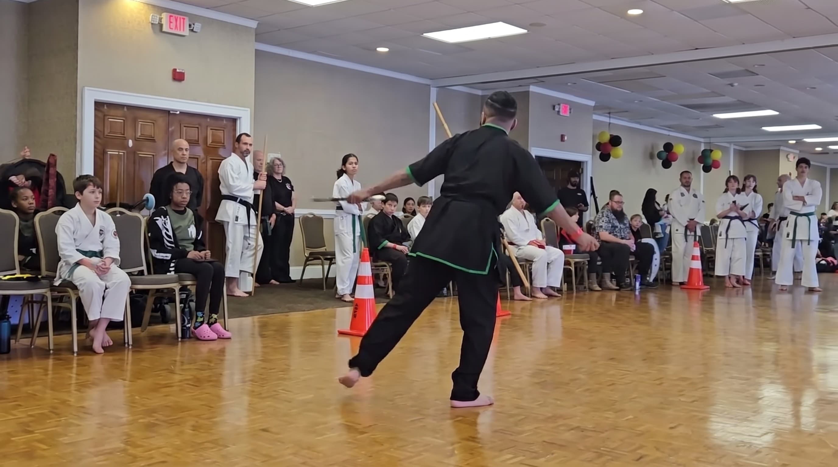 A student performing a kung fu form on a wood floor