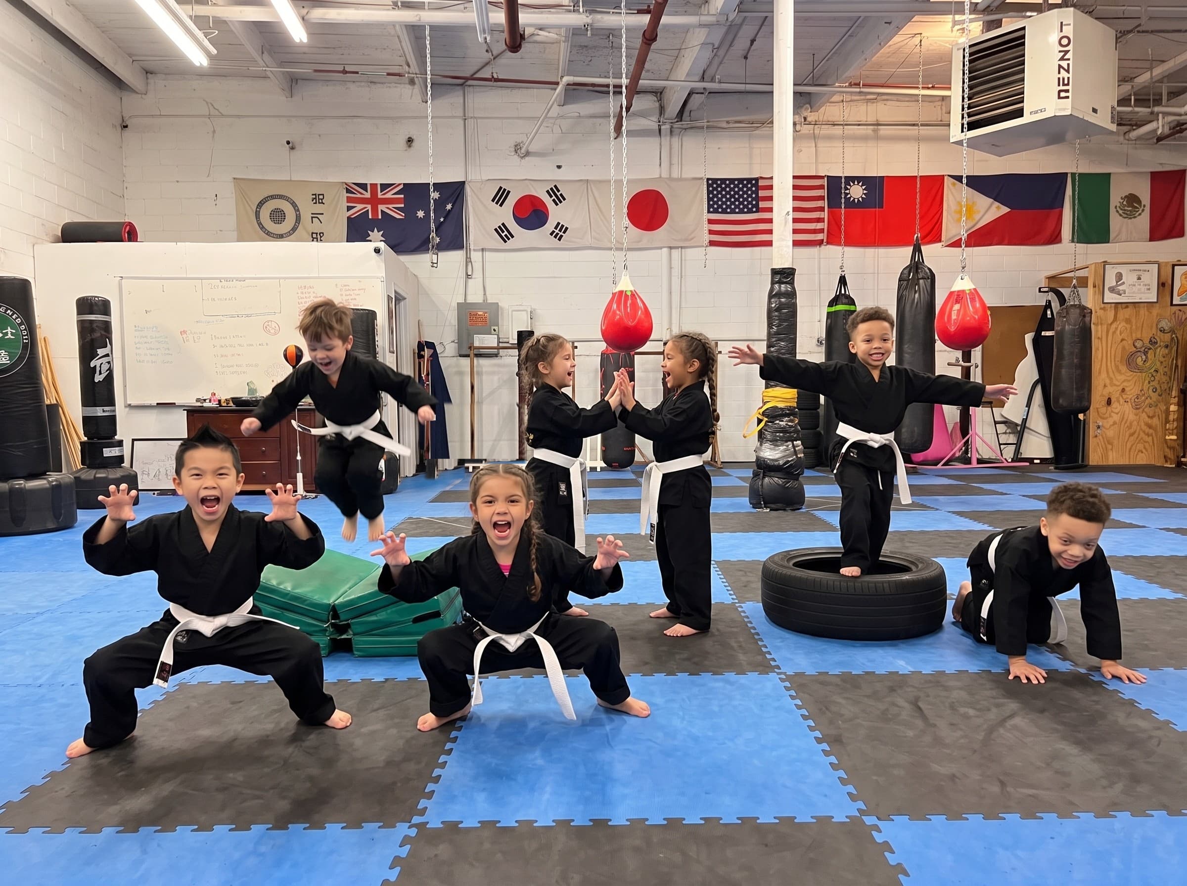 Seven young Tiny Tigers students playing tiger games on the mat